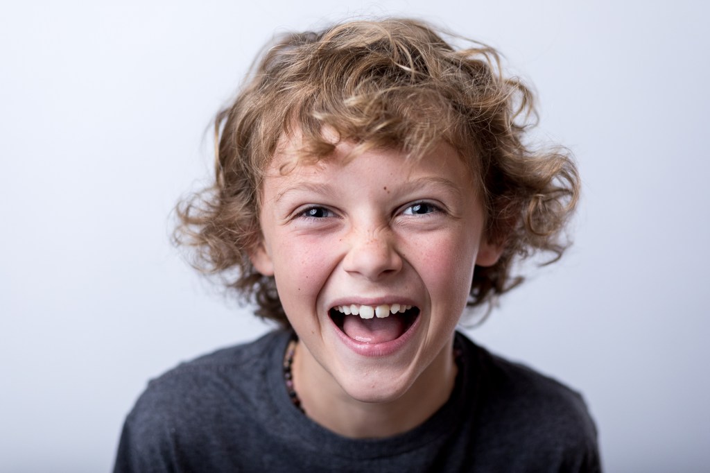 9 Year old, 4th grade boy laughing in a fine art school portrait.

